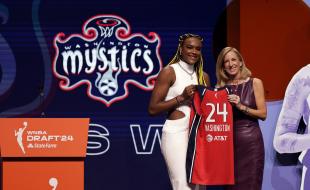 Aaliyah Edwards receives a Washington Mystics’ jersey after being chosen by the team during the WNBA basketball draft. (AP Photo/Adam Hunger)